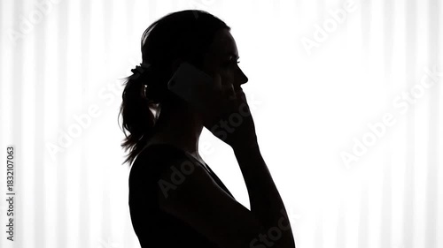 Silhouetted woman answers phone against a striped white background