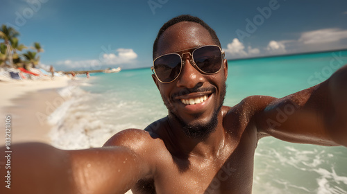 A smiling Black man enjoying a sunny beach day, wearing sunglasses and capturing a selfie by the turquoise water.