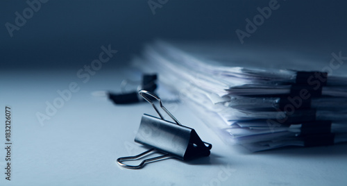 Stack of business papers with binder clips on gray background. Selective focus.
