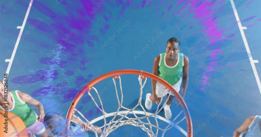Fototapeta premium Jumping green sleeveless jersey player in shorts reaching rim at gym with hoop and net, basketball