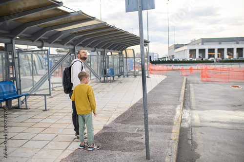 Wallpaper Mural Father and young son waiting for a bus at a bus stop. Family travel, everyday life, parenting moment, urban transportation, childhood and fatherhood concept, real people lifestyle. Torontodigital.ca