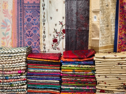 Photography Closeup view of stacked saris or sarees in display of retail shop, for use as indian textiles background