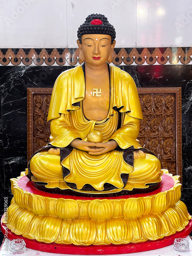 Golden Buddha statue resting on a red and gold lotus pedestal in a temple hall at Kek Lok Si, Penang, Malaysia. The figure is depicted in a traditional meditative pose.
