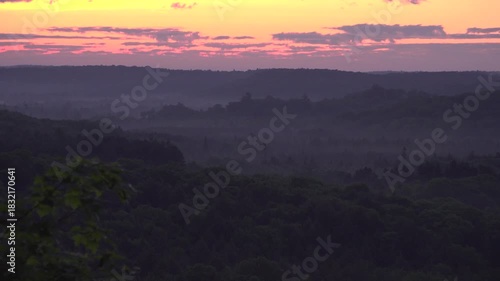 Wallpaper Mural A tranquil evening scene of a forest valley at sunrise. Dim silhouettes frame a gentle sky of red, orange and yellow conveying calm, quiet, and natural beauty. Torontodigital.ca