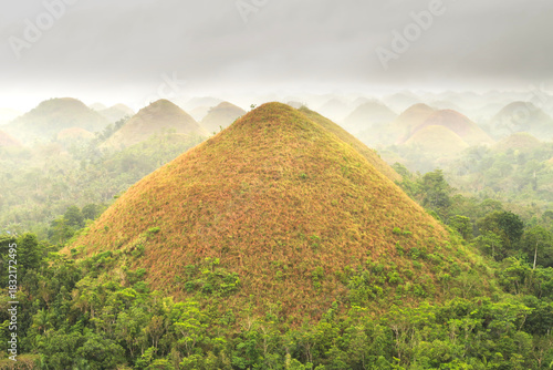 One of the Chocolate Hills on a rainy, foggy day, many more are seen in the background, Bohol Island, Philippines