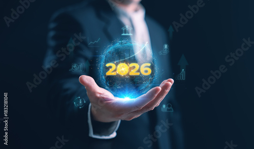 A businessman holding a glowing holographic globe with 2026, financial icons, and rising growth lines, representing global investment, economic trends, and future financial strategy in 2026.