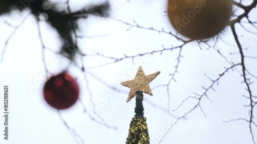 Christmas ornaments on christmas tree in a christmas market. Celebration for new year. Lights and some bright decorations looking shiny. Cloudy day time. Slow motion handheld shot 4k