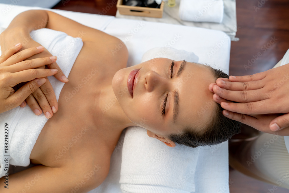 Fototapeta premium Caucasian woman enjoying relaxing anti-stress head massage and pampering facial beauty skin recreation leisure in dayspa modern light ambient at luxury resort or hotel spa salon. Quiescent