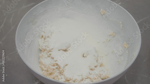 Fresh flour is added to a bowl filled with mixture, mixing ingredients for perfect cookie dough. Enjoy the process of baking tasty cookies from scratch.