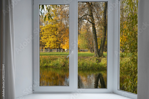 View from the window  on autumn landscape with a lake and bright yellow trees on the river bank.