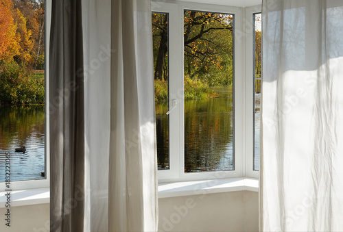 View from the window  on autumn landscape with a lake and bright yellow trees on the river bank.