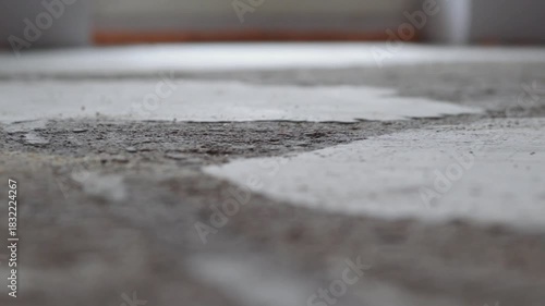 A broom sweeping a dusty floor in an unfinished room. Close-up shot with narrow focus area, Textured and blurry background with copy space