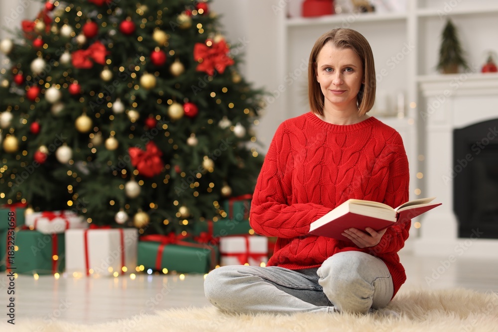 Fototapeta premium Beautiful woman with book in room decorated for Christmas
