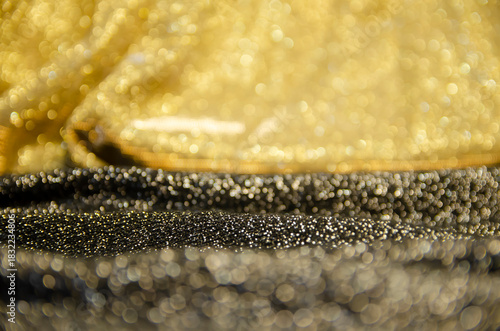 A bright holiday template. Background for congratulations. Gold and black shiny fabric. A screen saver with a Bokeh.