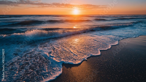 Golden hour's glow over the ocean waves and sandy shore at twilight.