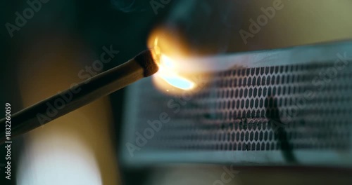 Slow motion close-up of a match being struck on a matchbox and bursting into flame at 1000 fps. Warm tones, detailed sparks, slow-motion ignition.