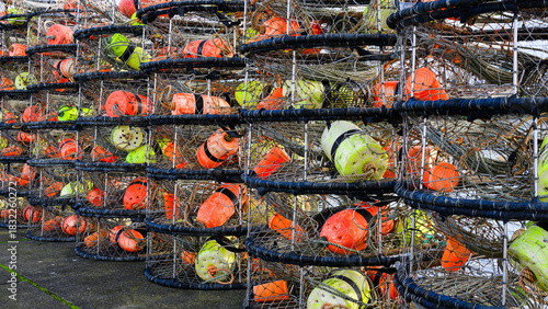 Row of stacked crab pot traps with colored floats on pier