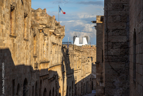 Fototapeta Naklejka Na Ścianę i Meble -  Historic cobblestone Street of the Knights in the Medieval City of Rhodes, Greece, featuring stone architecture, soft afternoon light and a timeless medieval atmosphere