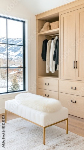 A sleek dressing room features light wood cabinets and a large window showcasing snow-covered trees in winter