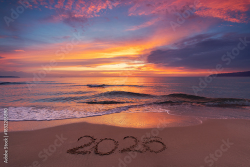 Fototapeta Naklejka Na Ścianę i Meble -  Scenic sunrise over the sea horizon and beach text Happy New Year 2026 on the sand