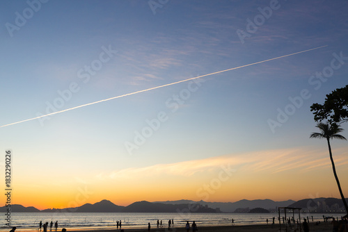 Sunset sky with airplane contrail over Santos beach, Brazil