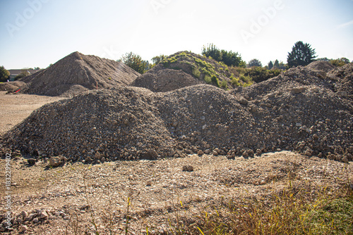 Piles of gravel and earth at an open construction or excavation site under bright sunlight