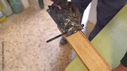 top view of Woodworker hands cutting a wooden board with a power circular saw in a workshop