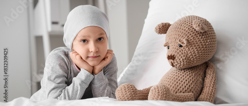 Little girl after chemotherapy with toy on bed in clinic. International Child...