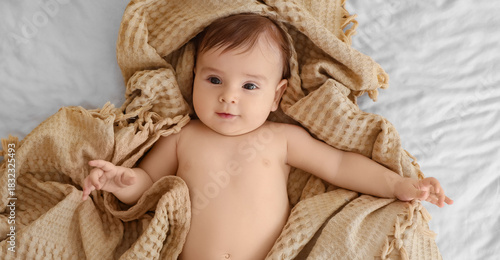 Cute little baby with beige plaid lying on bed, top view