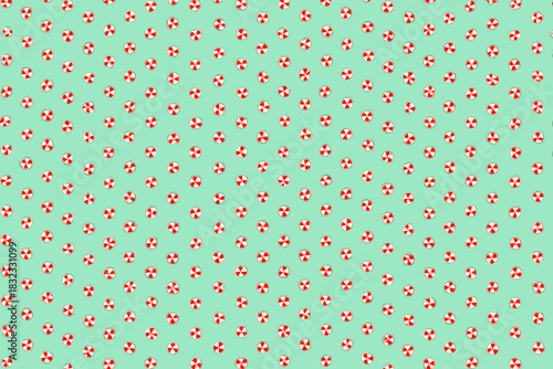 Seamless Pattern of Red and White Peppermint Candies on Green Background