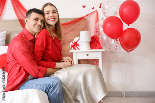 Young couple hugging in bedroom on Valentine's Day