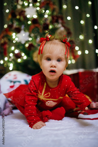 Little girl sitting near Christmas tree at the holiday