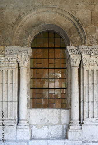 Arles, Saint-Trophime, Provence, France: fine art view of a Romanesque stone window and carved capitals. Subtle light revealing medieval textures and monastic architectural details.