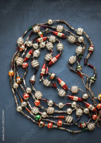 Old vintage Christmas partially broken glass beaded Tree necklace, top view on dark blue grey background, selective focuus