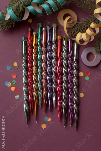 Old vintage Christmas ornaments glass icicles, top view on purple background with paper streamers, selective focus