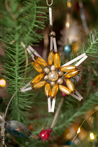 Branch of artificial Christmas tree decorated with vintage old glass beaded ornament snowflake close-up, selective short focus