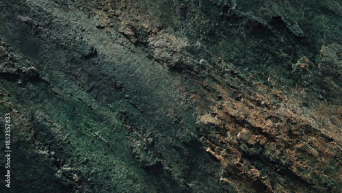 A rugged, dark green and earthy brown textured rock surface, showcasing natural striations, organic patterns, and weathered details.