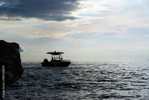Dramatic view: silhouette of a small boat in sea near the shore on a cold evening