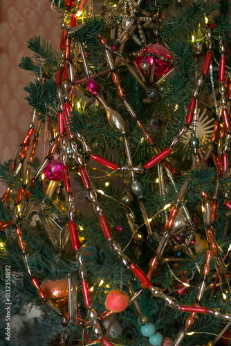 Artificial Christmas tree decorated with vintage old glass beaded necklaces in retro style, dark holiday background, selective focus