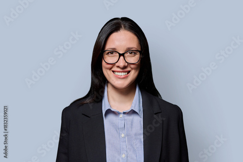 Portrait of smiling middle-aged businesswoman in black jacket on light studio background