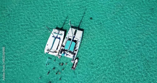 Aerial view of tourists swimming next to luxury catamarans on idyllic sea near Le Morne on Mauritius
