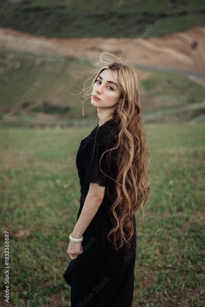 Fototapeta premium Woman With Long Wavy Hair Standing Outdoors in Natural Landscape