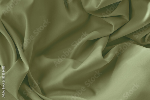 Olive green silk fabric background with folds. Copy space.
