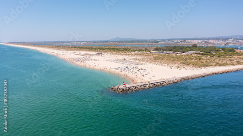 Obraz na plátně Scenic beach view with golden sands and turquoise waters, featuring a jetty and sunbathers enjoying a sunny day outdoors