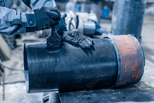 The metal pipe thread is painted with a brush with black paint or bitumen. Protection of metal pipes from corrosion. Preparation of oil drilling pipes