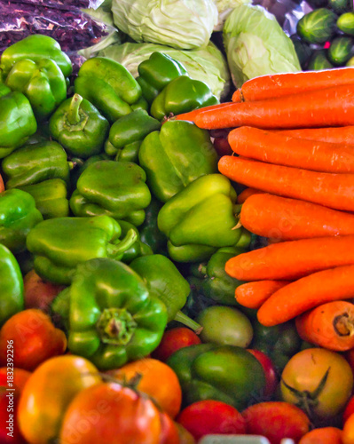 Green peppers and carrots on the market place in Cape Verde, Santiago island: colorful raw vegetables closeup photography.