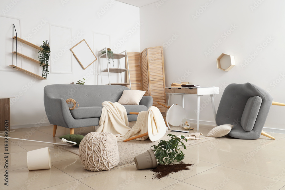Fototapeta premium Interior of messy living room with sofa, overturned table and broken things after earthquake