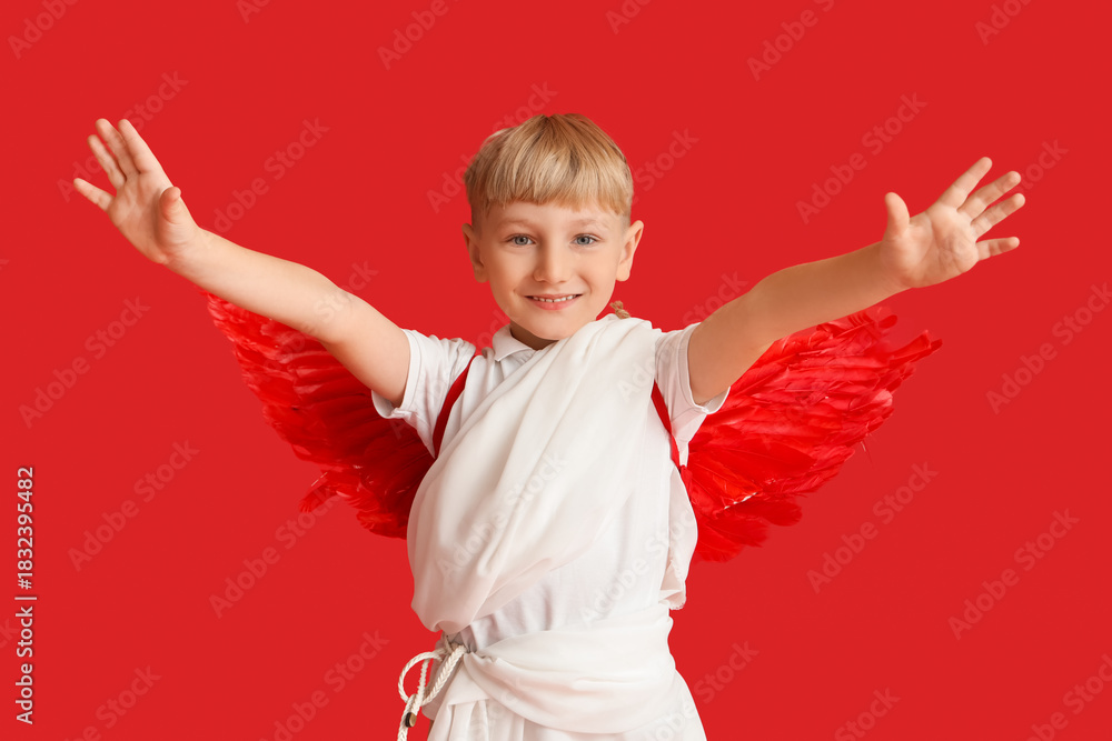 Obraz premium Cute little happy boy dressed as cupid on red background. Valentine's Day celebration
