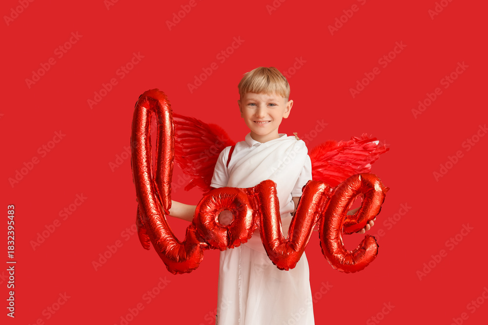 Obraz premium Cute little happy boy dressed as cupid with word LOVE made of balloons on red background. Valentine's Day celebration
