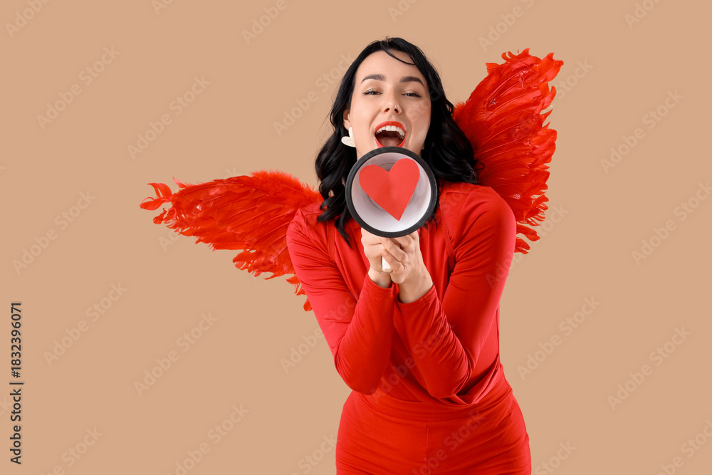 Obraz premium Beautiful young happy woman dressed as cupid with megaphone on beige background. Valentine's Day celebration